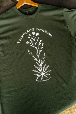Green t-shirt with white floral design and text on a hanger