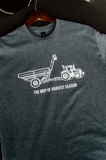 Gray t-shirt with white tractor graphic and text on a hanger against a dark background