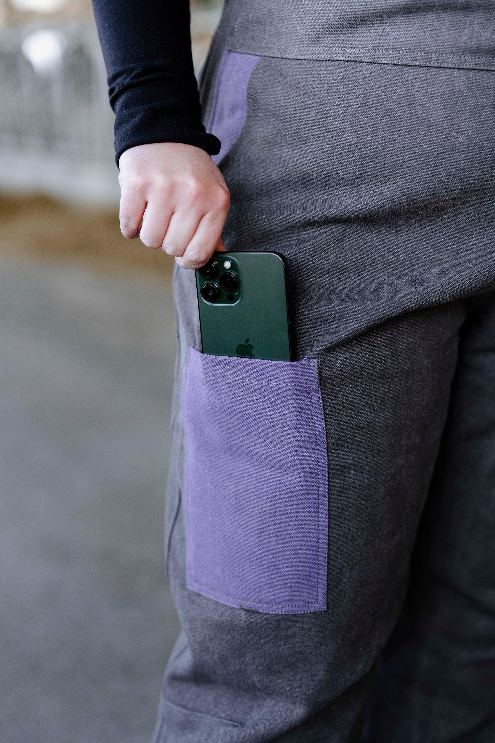 A person wearing lilac insulated overalls with a smartphone in the front pocket.