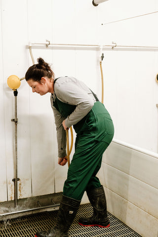 Lady using hose in green overalls and rubber boots