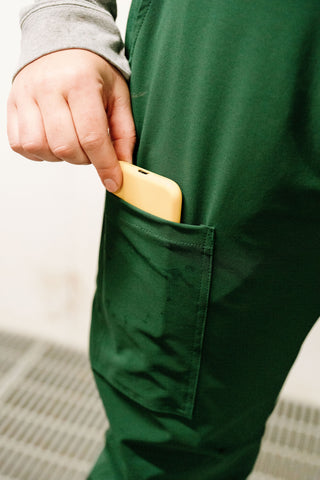 Person putting yellow object into dark green overalls